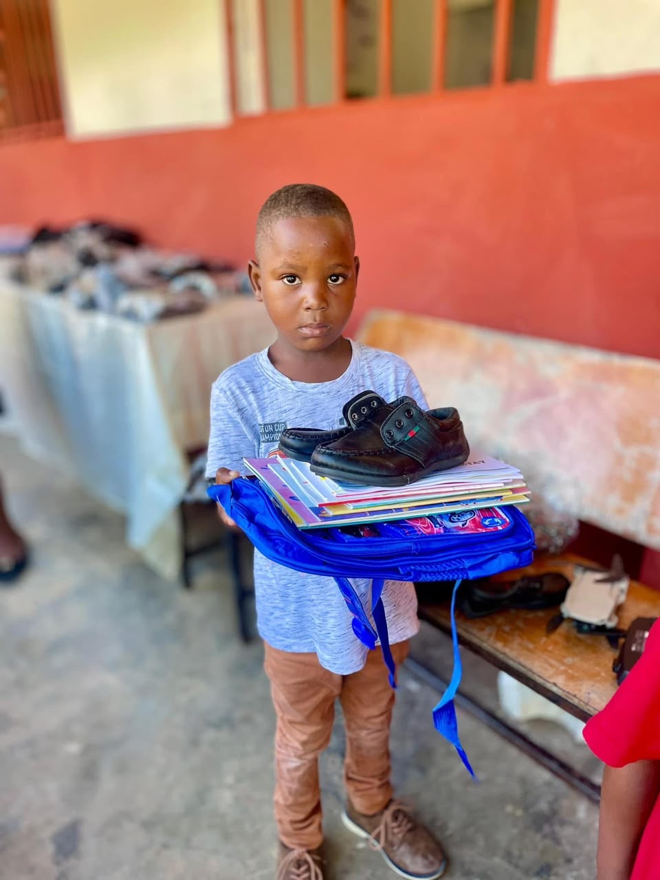 An orphan receives school supplies and shoes.